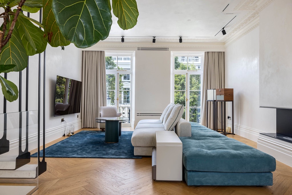 A bright London reception room with herringbone floors and tall garden-facing windows